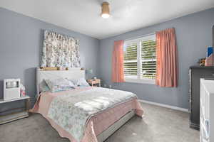 Carpeted bedroom with baseboards and a textured ceiling