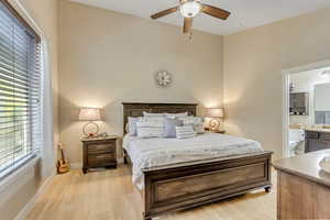 Main bedroom featuring light wood finished floors, ceiling fan, and ensuite bath
