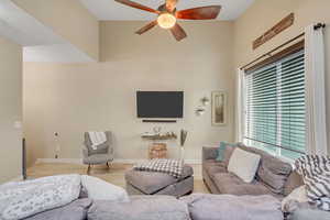 Living area featuring wood finished floors, a ceiling fan, and a towering ceiling