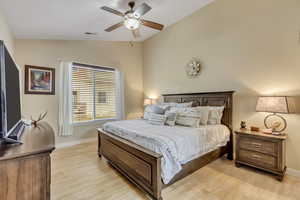 Main bedroom featuring vaulted ceiling, light wood-style flooring, and ceiling fan
