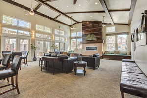 Living area with light colored carpet, beam ceiling, a fireplace, high vaulted ceiling, and recessed lighting