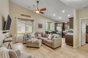 Living room with lofted ceiling, a ceiling fan, recessed lighting, and light wood-style flooring