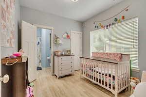 Bedroom featuring a nursery area and light wood-style flooring
