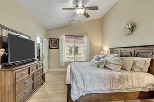 Main bedroom with lofted ceiling, ceiling fan, and light wood-style floors
