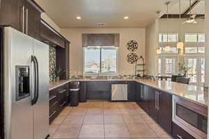 Kitchen featuring appliances with stainless steel finishes, dark brown cabinetry, decorative light fixtures, tasteful backsplash, and recessed lighting