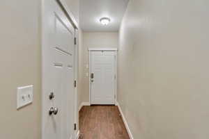 Doorway with baseboards and wood finished floors