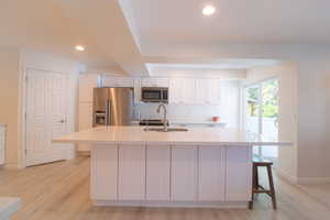 Kitchen featuring white cabinetry, a kitchen breakfast bar, light wood-style floors, and recessed lighting