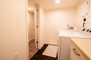 Laundry area featuring washing machine and dryer, dark tile patterned floors, and recessed lighting