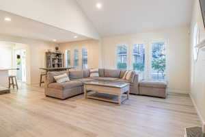 Living room featuring high vaulted ceiling, recessed lighting, and light wood finished floors