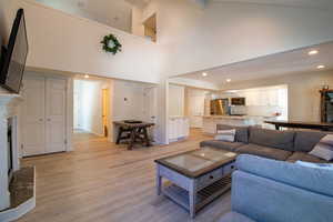 Living room featuring light wood finished floors, high vaulted ceiling, recessed lighting, and a high end fireplace