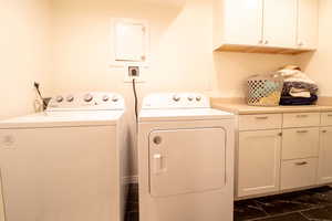 Laundry area with cabinet space, washer and clothes dryer, and dark marble finish flooring