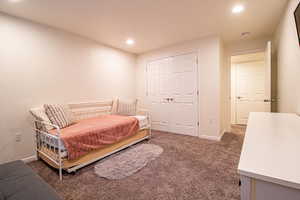 Carpeted bedroom with recessed lighting and a closet