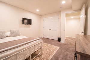 Bedroom with recessed lighting, light colored carpet, and a closet