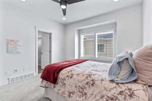 Carpeted bedroom with a ceiling fan and recessed lighting