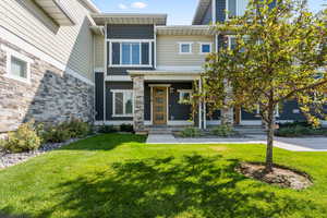 View of front of house featuring stone siding, a front lawn, and a porch