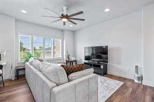 Living area with dark wood-style flooring, ceiling fan, and recessed lighting
