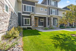 Property entrance with stone siding, covered porch, and a yard