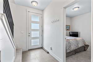 Entryway featuring light tile patterned floors, a textured ceiling, and stairway