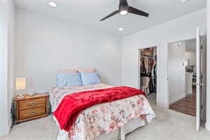 Carpeted bedroom with a walk in closet, recessed lighting, and ceiling fan