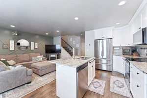 Kitchen featuring stainless steel appliances, white cabinetry, open floor plan, a kitchen island with sink, and recessed lighting