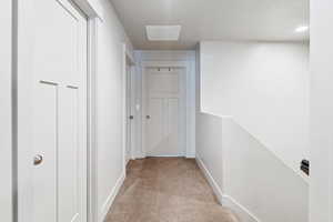 Corridor featuring light carpet and a textured ceiling