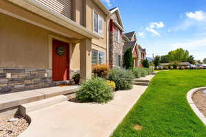 Property entrance featuring stone siding, a residential view, a yard, and stucco siding