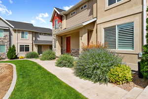 Entrance to property featuring stone siding, stucco siding, and a lawn