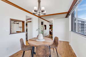 Dining area featuring light wood-style floors, a chandelier, crown molding, and a textured ceiling