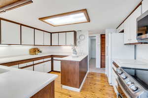 Kitchen with white cabinetry, light countertops, and appliances with stainless steel finishes