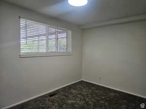 Spare room featuring dark colored carpet and baseboards
