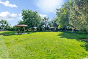 View of grassy yard featuring a gazebo, a patio area, and view of scattered trees