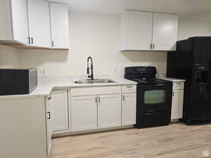 Kitchen featuring black appliances, white cabinets, light countertops, and light wood-style floors
