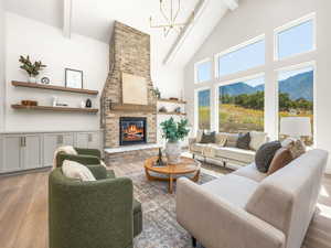 Living room featuring light wood-style floors, high vaulted ceiling, beamed ceiling, a brick fireplace, and a mountain view
