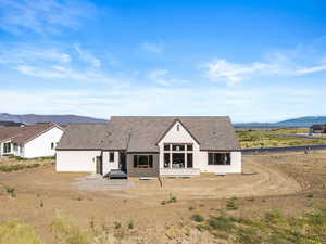 Back of house with a mountain view, a patio area, and roof with shingles