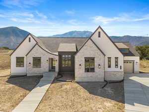 View of front of house with a mountain view, stone siding, a shingled roof, and stucco siding