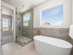 Bathroom featuring a freestanding bath, a stall shower, tile walls, tile patterned floors, and recessed lighting