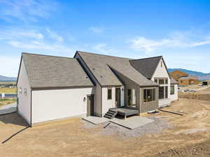 Back of house featuring a mountain view, roof with shingles, and board and batten siding