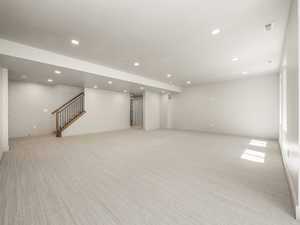 Below grade area featuring stairs, recessed lighting, and light carpet