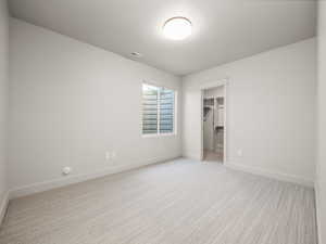 Unfurnished bedroom with a walk in closet and light colored carpet