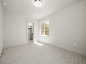 Unfurnished bedroom featuring a walk in closet and carpet flooring