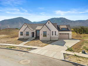 View of front of property featuring concrete driveway, a mountain view, brick siding, and a shingled roof
