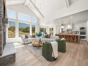 Living area featuring a fireplace, beamed ceiling, light wood-type flooring, high vaulted ceiling, and recessed lighting