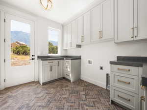 Laundry room featuring hookup for a washing machine, brick patterned flooring, a mountain view, electric dryer hookup, and cabinet space