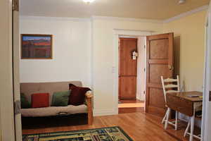 Living area with ornamental molding and wood finished floors