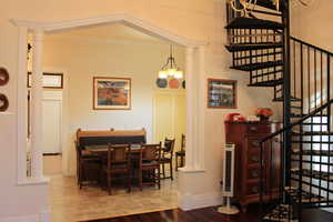 Dining area featuring ornate columns, stairway, wood finished floors, and crown molding