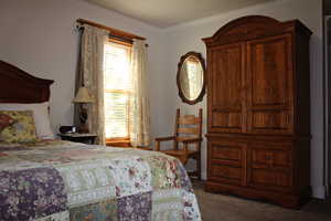 Bedroom featuring crown molding and dark carpet
