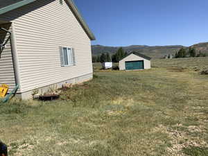 View of home's exterior with a mountain view, an outbuilding, a garage, and a lawn