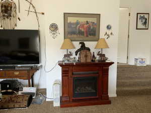 Living area featuring carpet, a glass covered fireplace, and stairway