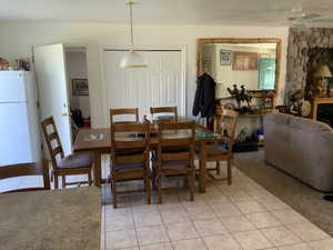 Dining area with light tile patterned floors, ceiling fan, a fireplace, and light colored carpet