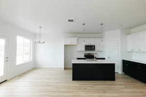 Kitchen with dark cabinetry, white cabinets, and pendant lighting